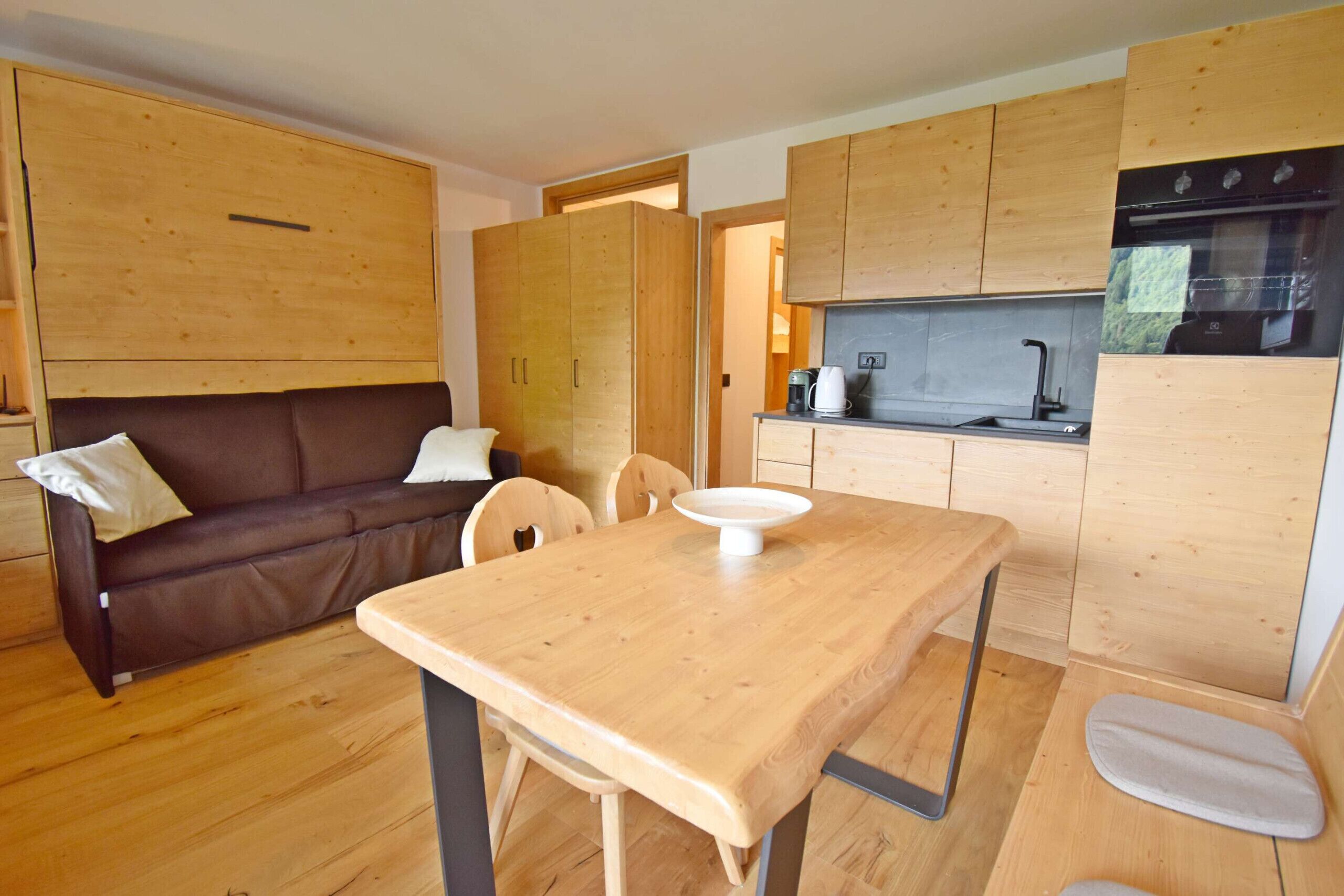 Una cocina compacta con muebles de madera, una mesa de comedor y un sofá en una zona de estar acogedora.
