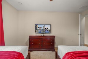 Ein Schlafzimmer mit zwei Betten, einem Schminktisch und einem an der Wand befestigten Fernseher.