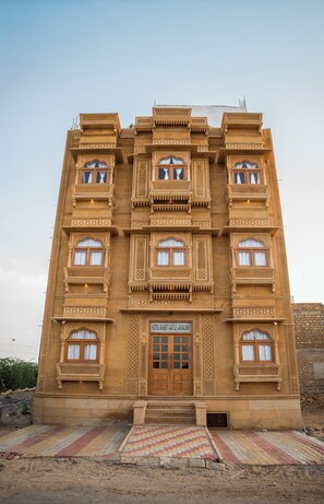 Un edificio de varios pisos con detalles arquitectónicos intrincados, una entrada central con puerta de madera y un cartel que indica que es un hotel.