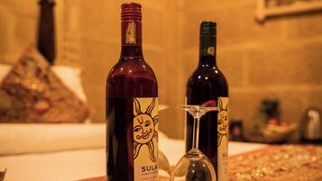 Uma garrafa de vinho tinto Shiraz Cabernet da Vinícola Sula, safra 2015, e uma taça de vinho em um tabuleiro com um jogo americano decorativo.