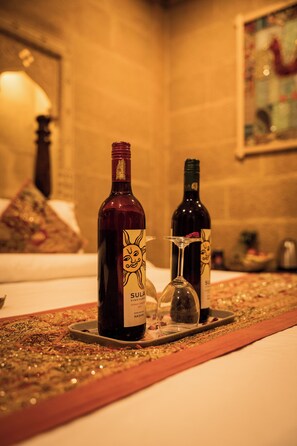 Una botella de vino Shiraz Cabernet de Sula Vineyard 2015 y una copa sobre una bandeja con camino de mesa decorativo.