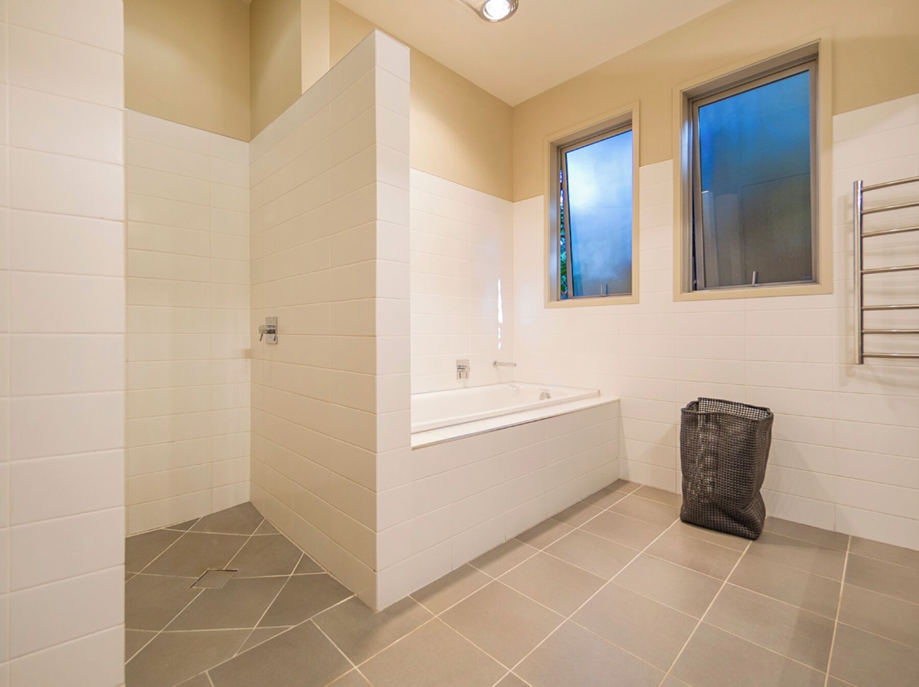 Ein Badezimmer mit weißen Fliesen, einer Badewanne, einer Duschkabine und einem Fenster.