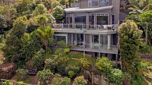 A modern multi-story house with a balcony, surrounded by lush greenery. - Bay View Escape - Whitianga Holiday Home (Whitianga)