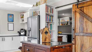 A kitchen with white cabinets, a wooden island, and bookshelves filled with books. - Kakepuku View and Spa Retreat - Te Awamutu (Te Awamutu)