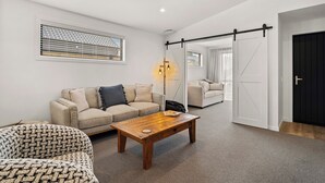 Een moderne woonkamer met een bank, een fauteuil met een patroon, een houten salontafel en een vloerlamp.