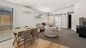 Een moderne woonkamer met een eethoek, een bank, een salontafel en een televisie.