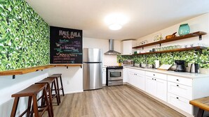 A modern kitchen with white cabinets, a stainless steel refrigerator, and a chalkboard menu listing breakfast items.