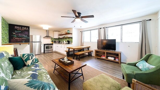 A living room with a sofa, coffee table, TV, and a dining area with a table and chairs.