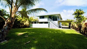 A modern two-story house with a covered patio and a well-maintained lawn.