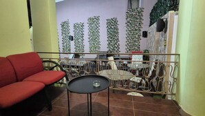 A balcony with a red sofa, a small round table, and a metal railing.
