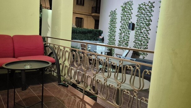 A balcony with a red sofa, a small round table, and a metal railing.