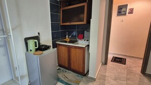 A compact kitchen with a sink, a kettle, and a small countertop.