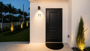 A modern house exterior with a black door, a white wall, and a small porch area. - Stylish Stay Near Hard Rock Stadium (North Miami Beach)