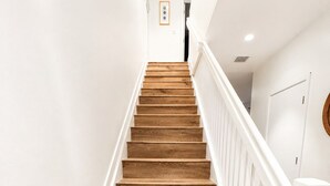 A wooden staircase with white railings, leading to a door with a circular mirror. - Stylish Stay Near Hard Rock Stadium (North Miami Beach)