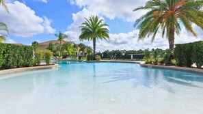 A swimming pool with clear blue water, surrounded by palm trees and a hedge. - Bright and contemporary resort property - Recently updated/themed - within 10 mins of Disney (Kissimmee)