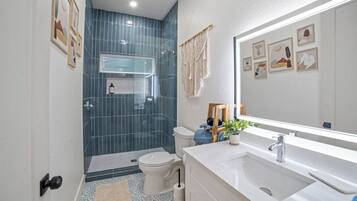 A modern bathroom with a shower, toilet, and sink.