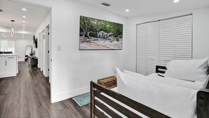 Une chambre à coucher avec un lit, une tête de lit en bois, un mur blanc, un tableau et une armoire.