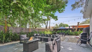 Un espace extérieur aménagé en terrasse, avec des meubles en osier, un foyer et un barbecue.