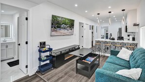 Un salon moderne avec un canapé, une table basse, un téléviseur et une cheminée.