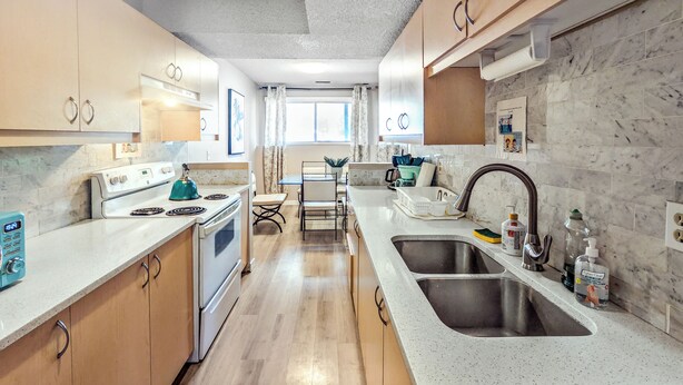 Une cuisine moderne avec des meubles en bois, un évier en acier inoxydable et une cuisinière intégrée.
