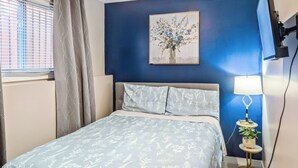 Une chambre à coucher avec un lit, une table de chevet, une lampe et un tableau au mur.