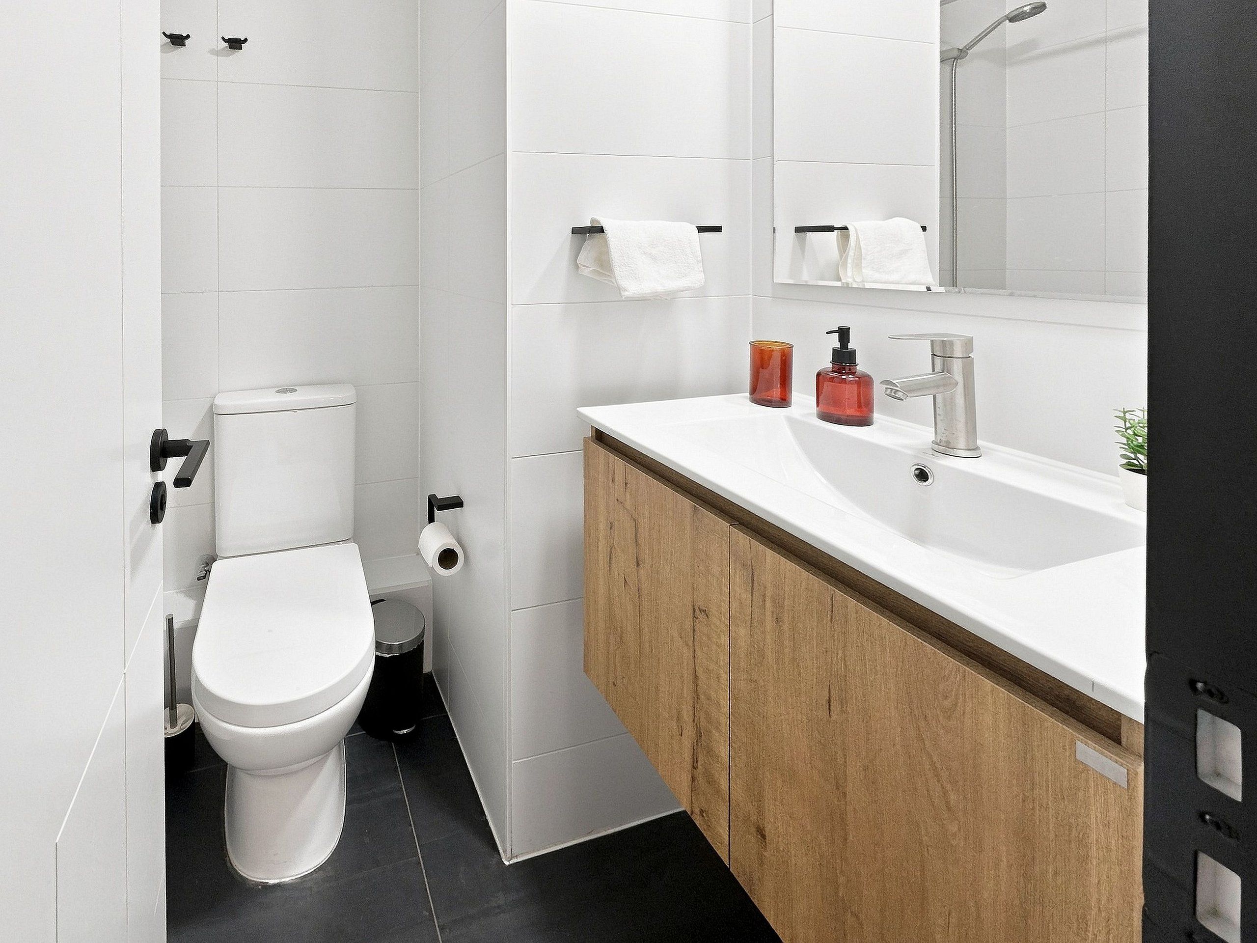 A modern bathroom with a toilet, sink, and mirror.