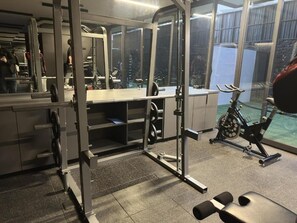 Une salle de sport équipée de matériel de musculation, d’un banc et d’un vélo.