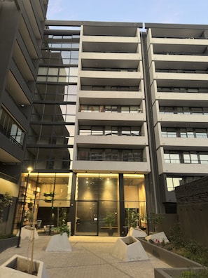 Un immeuble à plusieurs étages doté d’une architecture moderne, avec des balcons et de grandes fenêtres.