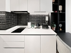 Une cuisine moderne avec un dosseret de carreaux noirs, des meubles blancs et une plaque de cuisson à induction intégrée.