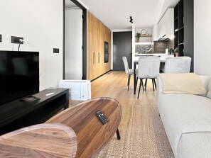 Una sala de estar moderna con un televisor de pantalla plana, una mesa de centro de madera y un sofá gris.