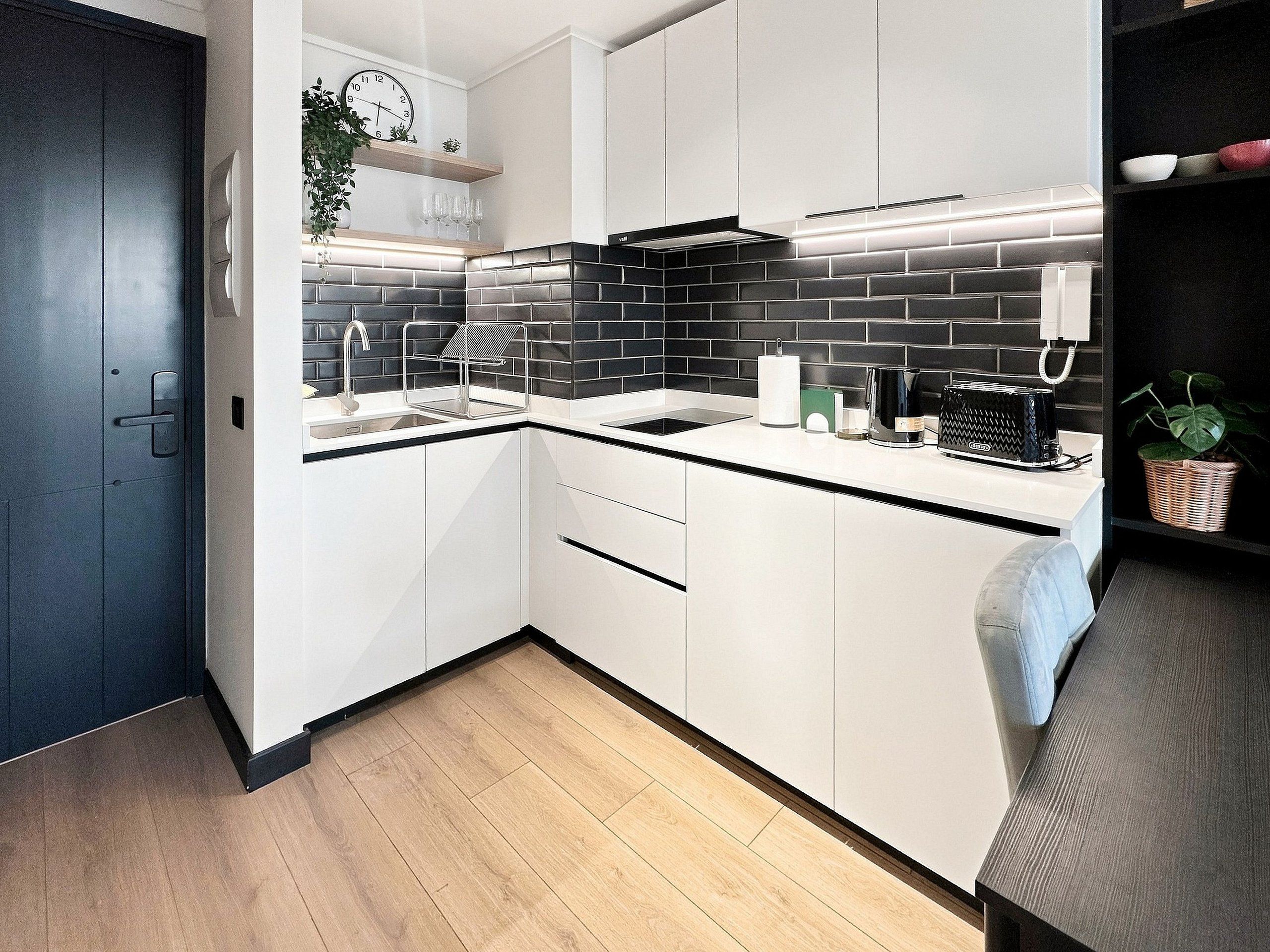 Eine moderne Küche mit weißen Schränken, einer schwarzen Fliesenrückwand und einer Holz Arbeitsplatte.