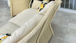 A wicker lounge chair with a cushion and a pillow, positioned in front of a glass door leading to a dining area. - The LemonDrop: 3-bedroom townhome in charming Lewes minutes away from Beaches! (Lewes)