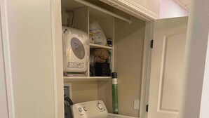 A laundry room with a washing machine, dryer, and storage shelves. - Charming tiny house in the mountains on a goat farm in Murphy, NC (Murphy)