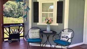 A porch with two chairs, a small table, and a grill. - Charming tiny house in the mountains on a goat farm in Murphy, NC (Murphy)