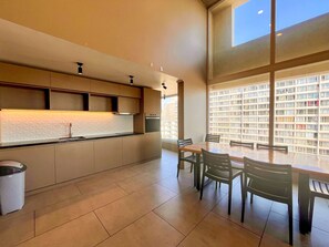 A modern kitchen with a dining area, large windows, and a view of a residential building. - Downtown Studio - Home Office & Fast WiFi (Santiago)