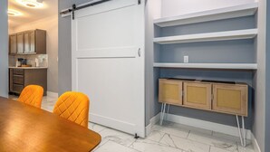 Una cucina moderna con mobili in legno, una porta scorrevole e un sistema di scaffalature a parete con cesti in vimini.