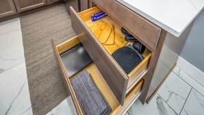 Una cucina con un cassetto in legno contenente un tagliere, una pentola nera e una confezione di Reynolds Wrap.