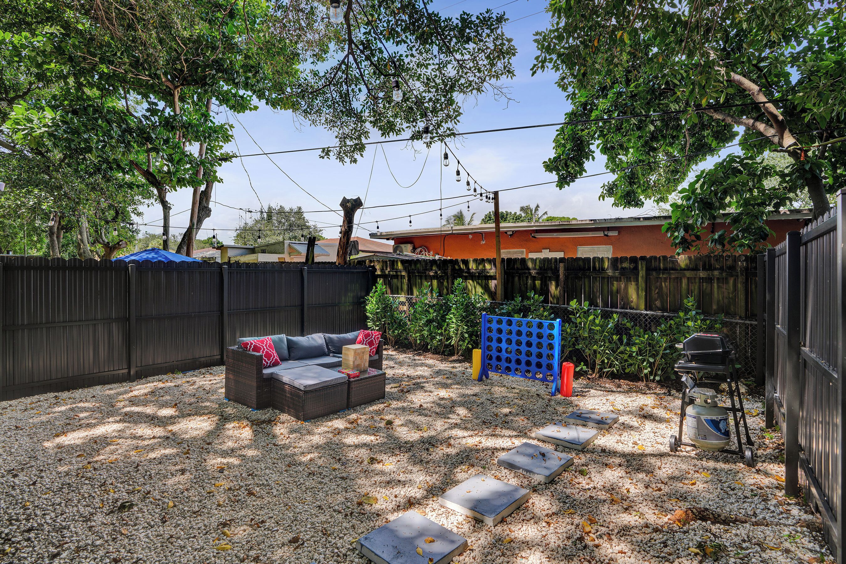 A backyard with a patio area, a grill, and a fenced garden.