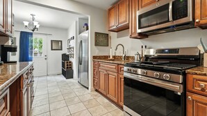 Una cocina moderna con gabinetes de madera, electrodomésticos de acero inoxidable y encimera de granito.