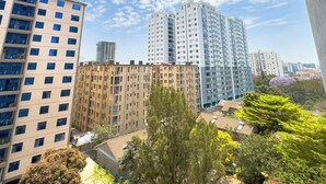 Een hoog appartementencomplex met meerdere verdiepingen en balkons, omgeven door groen en andere gebouwen.
