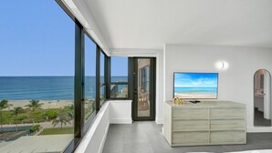 Habitación de hotel moderna con un balcón grande, televisión y vista a la playa.