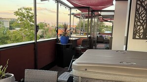 A covered outdoor seating area with a table and chairs, a hot tub, and a view of the cityscape. - Downtown rooftop, hot tub retreat adjacent to RiNo & Lodo Walk score of 95! (Denver)