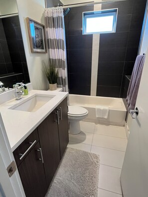 Une salle de bain moderne équipée d’une douche, de toilettes et d’une baignoire.