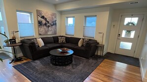 A living room with a sectional sofa, a coffee table, and a large abstract painting. - Downtown rooftop, hot tub retreat adjacent to RiNo & Lodo Walk score of 95! (Denver)
