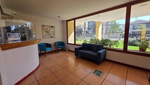 A room with a large window, a sofa, two chairs, and a small table with a sign. - Oceana Suites Providencia (Santiago)