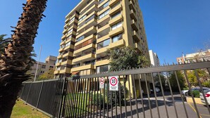 A multi-story residential building with balconies, a gated parking area, and a clear blue sky. - Oceana Suites Providencia (Santiago)