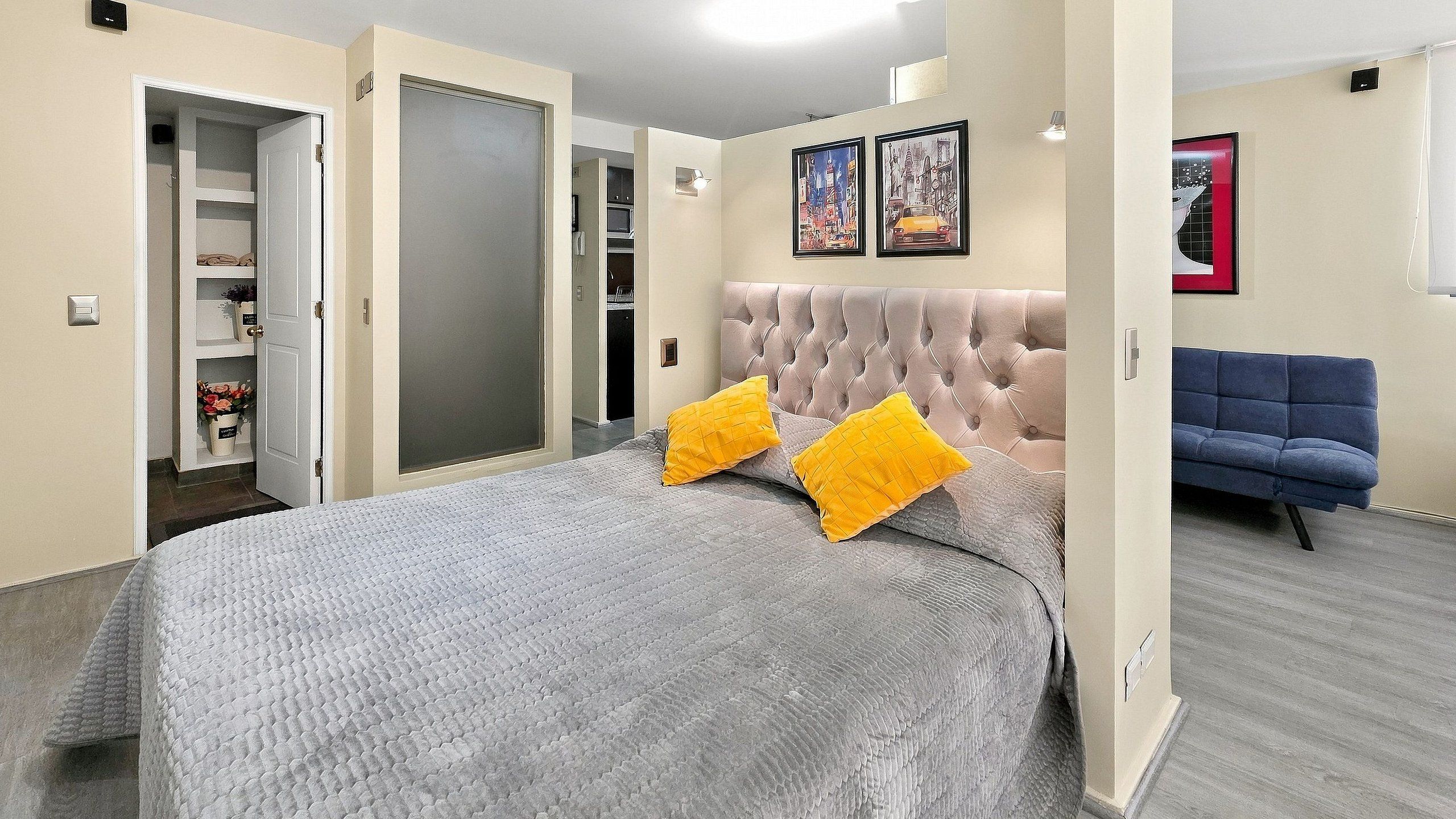 A bedroom with a bed, a wardrobe, a door, and a blue sofa.