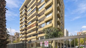 Un immeuble résidentiel à plusieurs étages, doté de balcons, d’une clôture en métal et d’un panneau indiquant qu’il est interdit de se garer.