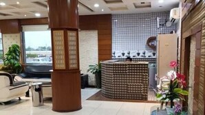 A hotel lobby with a reception desk, seating area, and a large pillar. - Aman Home 1 for serviced appartments (Riyadh)