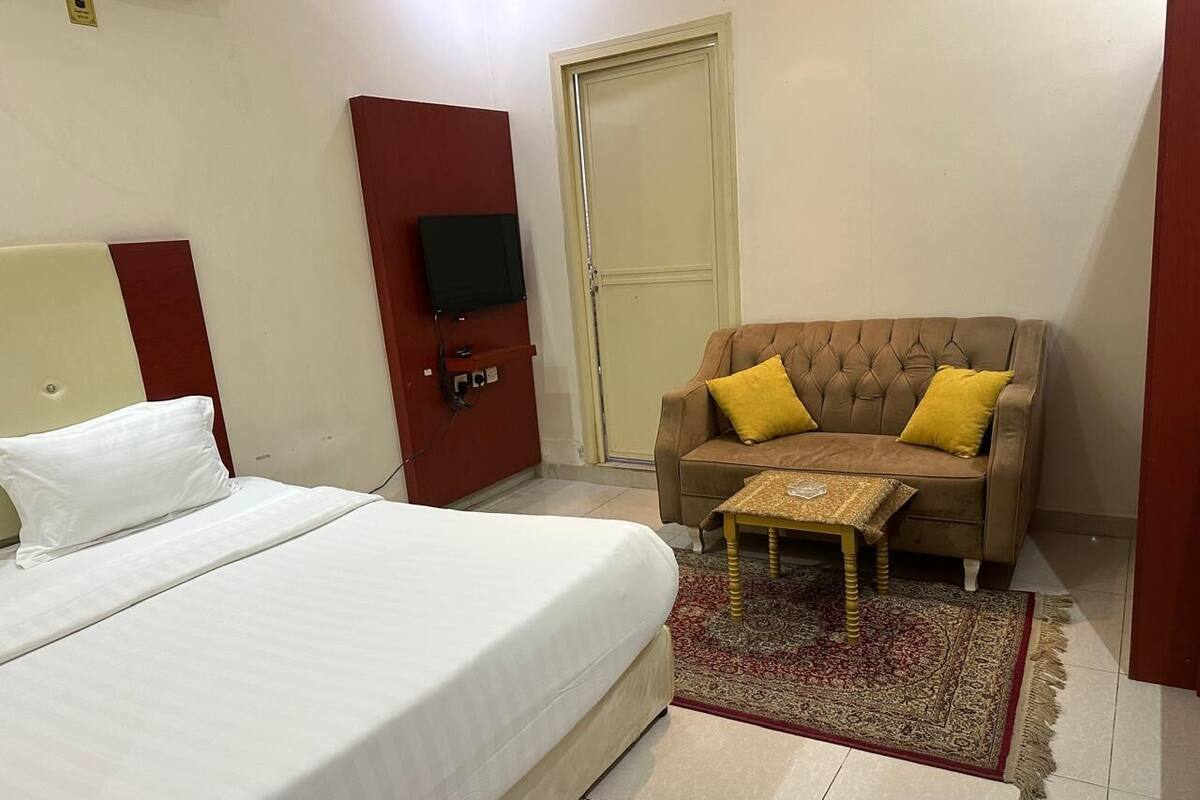 Ein Hotelzimmer mit Bett, einer Couch, einem kleinen Tisch und einem Fernseher.